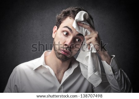 young man wipes sweat from his forehead with a handkerchief