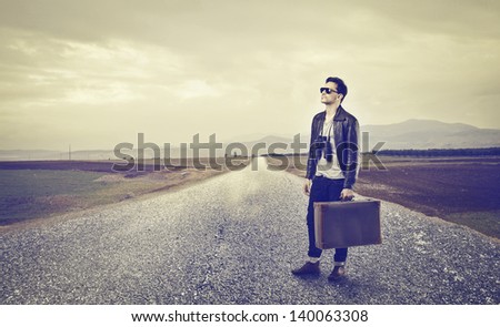 young man with luggage on a desert road