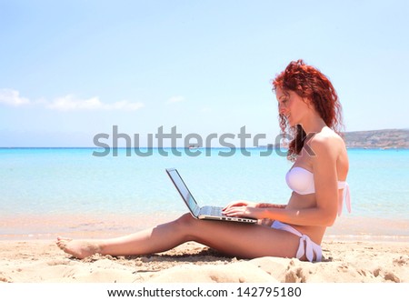 beautiful woman writes to the computer at the beach
