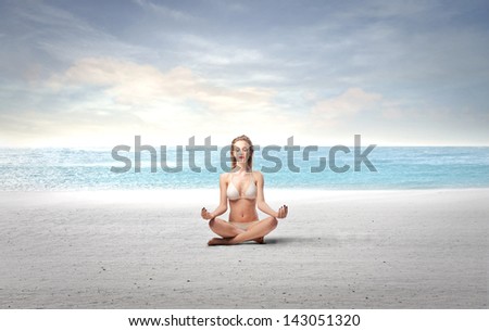 beautiful woman in bikini on the beach doing meditation