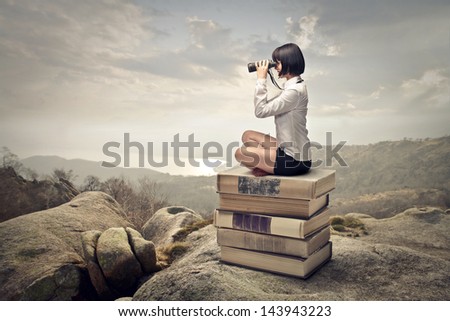 Beautiful Woman Sitting On A Pile Of Old Books Watching With Binoculars