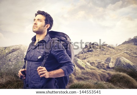 handsome man with a sack on his back walking in the mountains