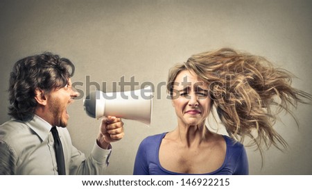 angry businessman screaming with megaphone to a woman