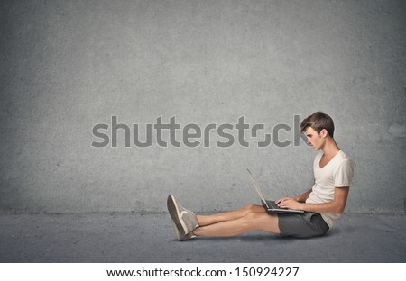 young boy working at the computer sitting on the floor