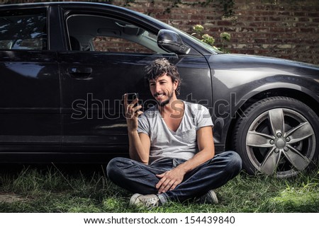 handsome man sitting on the grass with smartphone