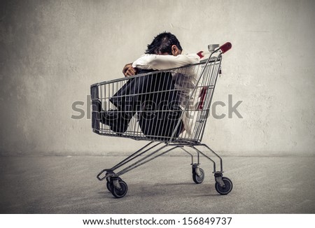 desperate businessman sitting in the shopping cart