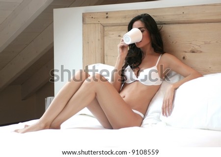A beautiful woman on the bed with a cup
