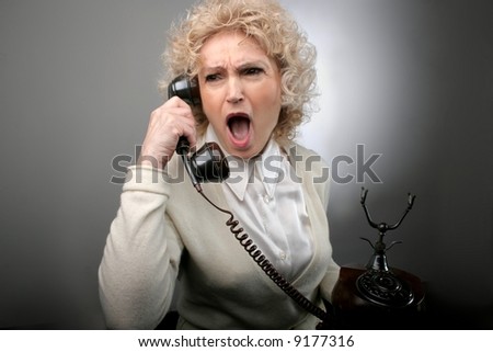 a senior woman with a screaming expression at the telephone
