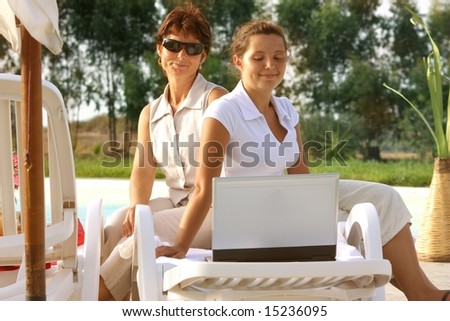 two woman with a laptop in  swimming pool