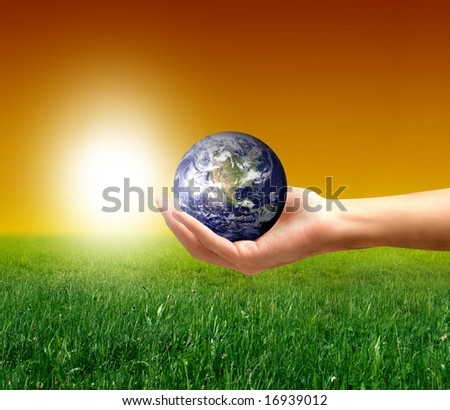 a hand with a globe and a grass field