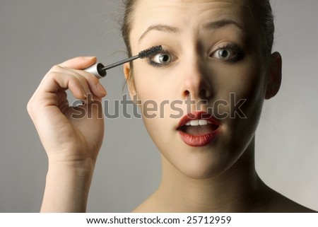 Beautiful woman putting mascara on her eyelash, daily morning routine