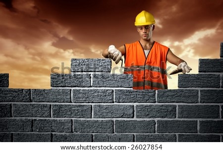 Mason in a hardhat building brick wall