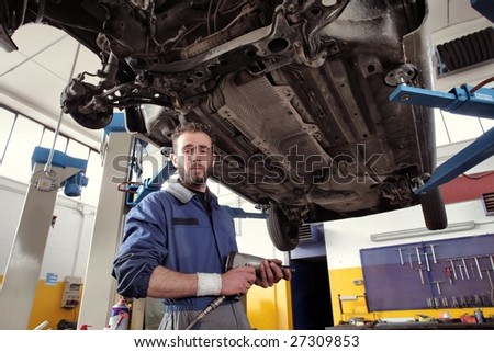 auto mechanic with a wrench under a car