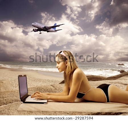 sexy girl using laptop against a sea scape with an airplane flying