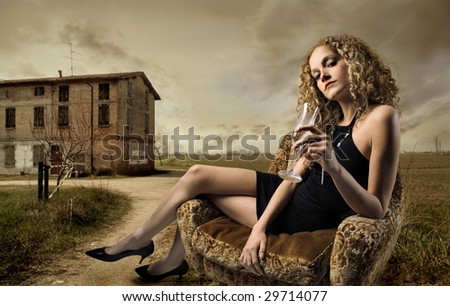 girl sitting on armchair with glass of wine in the countryside