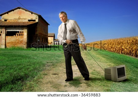 senior businessman pulling an old computer in the countryside