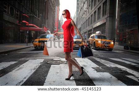fashionable girl with shopping bags crossing a city street