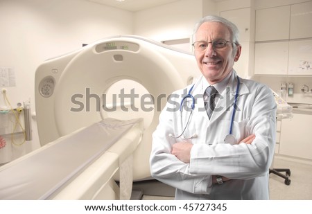 Senior doctor standing next to a CAT-scan machinery