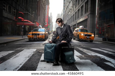 Portrait of a businessman sitting on his luggage in the middle of a city street