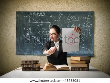 Portrait of a teacher sitting in front of a blackboard and holding a paper sheet with a bad mark on it