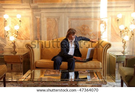 Portrait of a businessman sitting in a sofa in a luxury hotel and working on a laptop