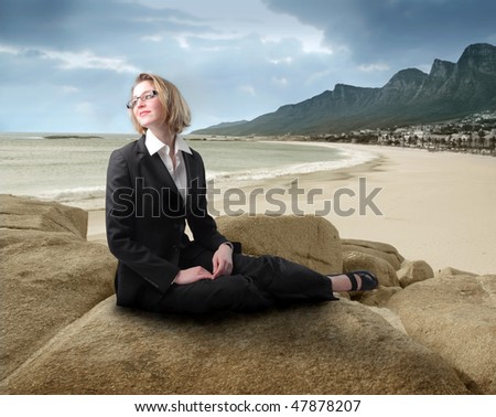 Portrait of a businesswoman sitting on a rock at the seaside