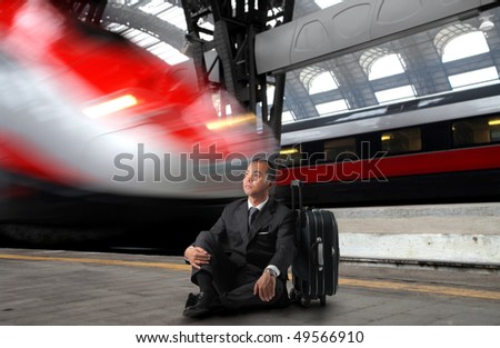 Japanese businessman sitting against a suitcase in a train station