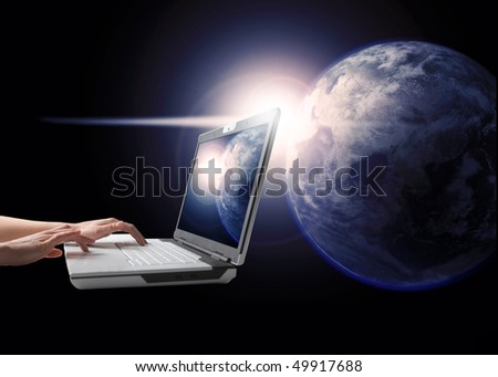 View of the earth with light on the background and man\'s hands working on a laptop