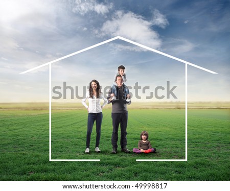Family surrounded by the form of a house on a green meadow