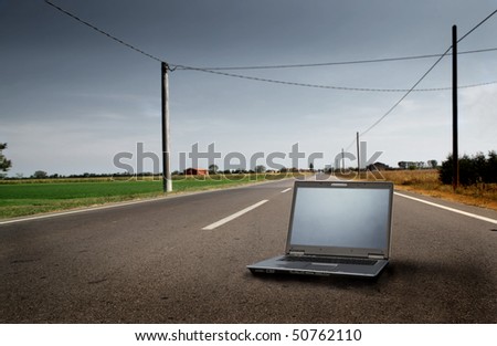 Laptop lying on a countryside road