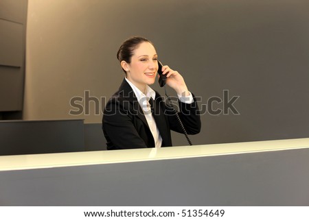 smiling businesswoman at the reception desk at the telephone