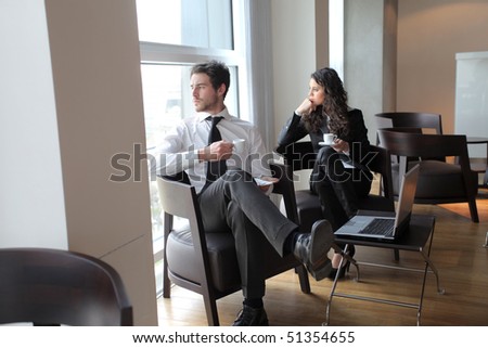 Two business people sitting on armchairs during coffee pause