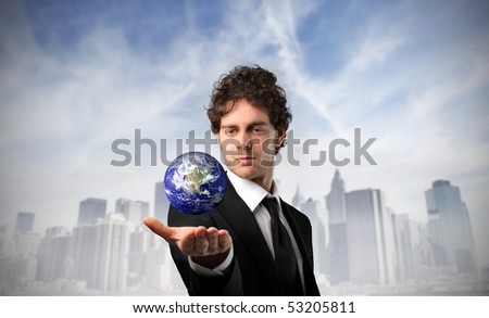 Businessman holding the earth in his hand with cityscape on the background