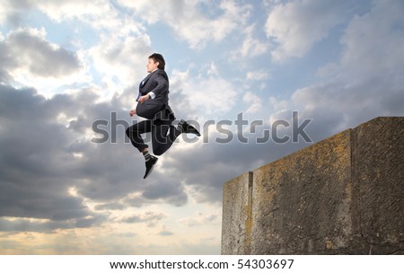 Businessman throwing himself from a rock into the void