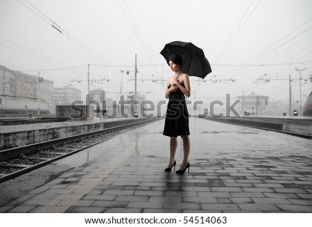 Woman with umbrella standing on the platform of a train station