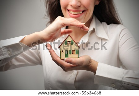 Smiling woman holding the model of a house