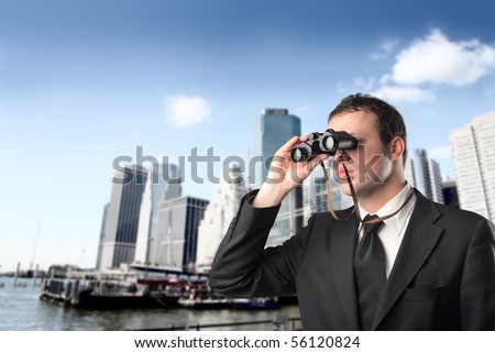 Young businessman with binoculars with cityscape on the background