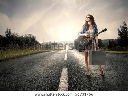 stock photo Woman holding a guitar standing on a countryside road