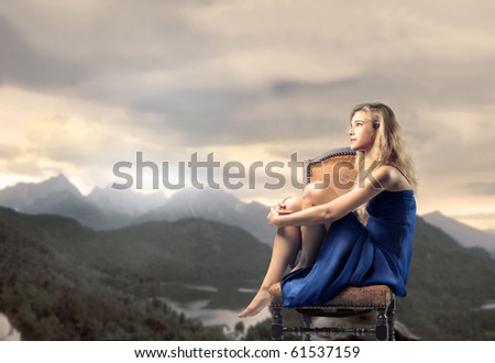 Young woman sitting on a rock with mountains at dawn on the background
