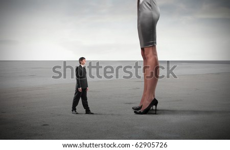 Tiny businessman standing in front of huge woman's legs
