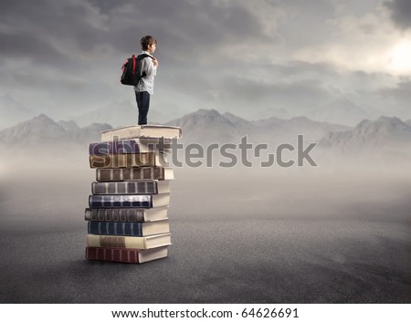 Child with rucksack standing on a stack of books