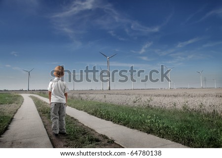 Child standing in front of wind turbines