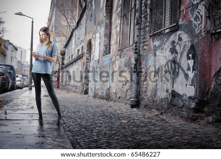 Beautiful young woman using a mobile phone on a city street full of graffiti