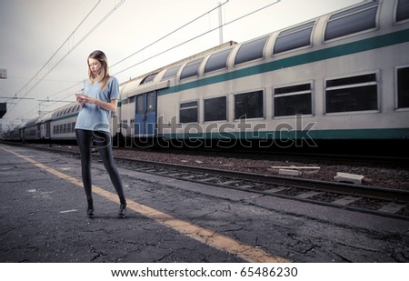 Beautiful young woman using a mobile phone on the platform of a train station