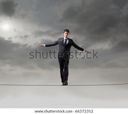 Businessman standing on a rope over the void