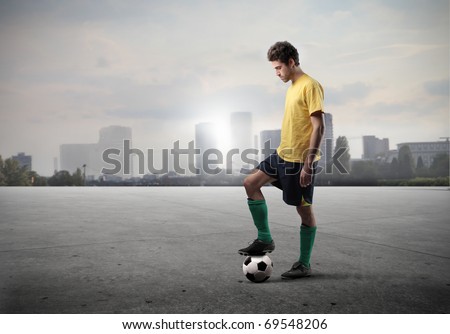 Football player standing on a field with cityscape on the background Football player standing on a field with cityscape on the background