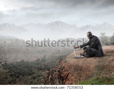 African businessman using a laptop on a mountain