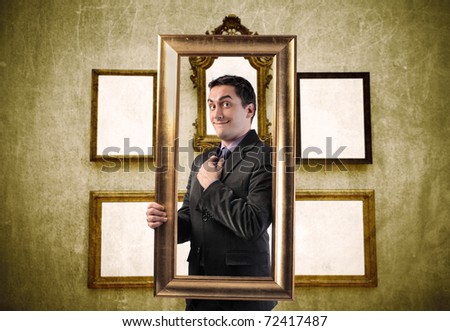 Smiling elegant man holding a frame with empty frames on the background