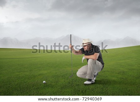 Golf player on a green meadow observing a golf ball
