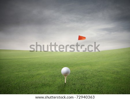 Golf ball on a green meadow with red flag on the background